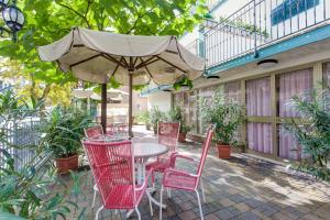patio con tavolo, sedie e ombrellone di Hotel Residence Des Bains a Cesenatico