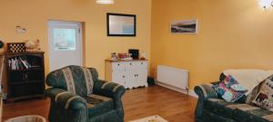 a living room with two chairs and a white cabinet at Luxury 3 bedroom house with peaceful garden, sleeps 6 and 2 mins to beach in Bundoran