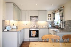 a kitchen with white cabinets and two chairs in it at The Hoglets in Goostrey