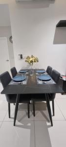 una mesa de comedor negra con sillas y un jarrón de flores en Continew Residence by Mikey - Premium Unit, en Kuala Lumpur