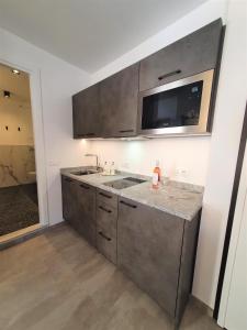 a kitchen with a sink and a microwave at BAUR SUITE - Regarda Travel in Bardolino