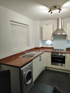 a kitchen with a washer and a sink and a stove at StayNEC LAMPREY- Lux Apartment - Birmingham - For Company, Contractor & Leisure Stays NEC, HS2, JLR, Airport in Kingshurst