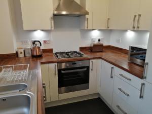 a kitchen with white cabinets and a stove top oven at StayNEC LAMPREY- Lux Apartment - Birmingham - For Company, Contractor & Leisure Stays NEC, HS2, JLR, Airport in Kingshurst