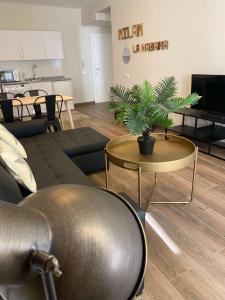 ein Wohnzimmer mit einem Sofa und einem Tisch mit einer Pflanze in der Unterkunft Apartamentos San Miguel in Torremolinos