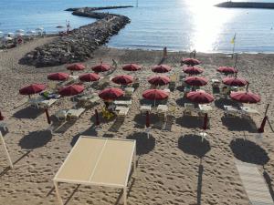 a group of red umbrellas and chairs on a beach at MIIO HOTEL in San Vincenzo