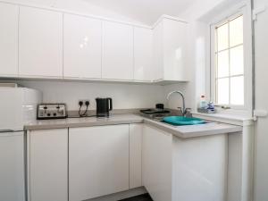 a white kitchen with white cabinets and a sink at Dolphin Cottage in Banff