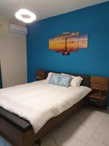 a bedroom with a bed with a blue wall at A Ground Floor Maisonette - Mellieha Bay in Is-Sellum