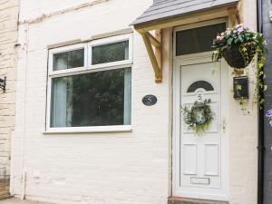 Una puerta blanca de una casa con una corona. en Appletree Cottage, en Chesterfield
