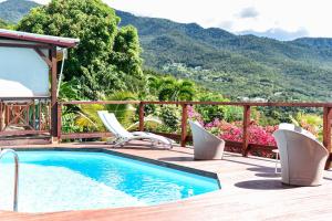 a swimming pool with chairs and a view of mountains at Gites La Nantillaise in Bouillante