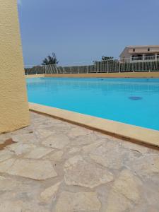 a large swimming pool with blue water next to a building at Ground floor studio with access to beach and pool in Le Barcarès