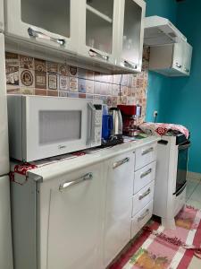 uma cozinha com armários brancos e um micro-ondas em Cantinho Santiago em Alto Paraíso de Goiás