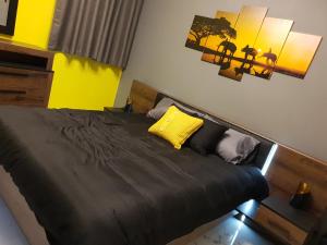 a bedroom with a black bed with a yellow pillow at A Ground Floor Maisonette - Mellieha Bay in Is-Sellum
