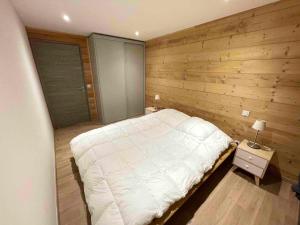 1 dormitorio con cama blanca y pared de madera en Chalet de 5 chambres avec sauna jardin clos et wifi a Les Orres en Les Orres