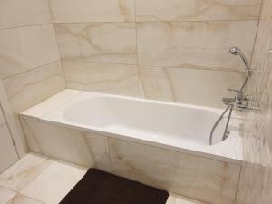a white bath tub with a shower in a bathroom at A Ground Floor Maisonette - Mellieha Bay in Is-Sellum
