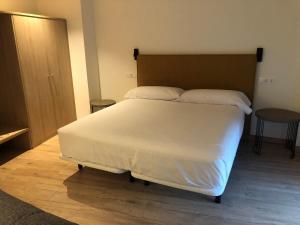 Un dormitorio con una gran cama blanca y una mesa en HOTEL MONTE PERDIDO, en Bielsa