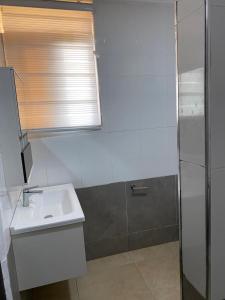 Un baño blanco con lavabo y ducha. en MILTON AVENUE SUITES, 2Bed, en Accra 2 fotos más