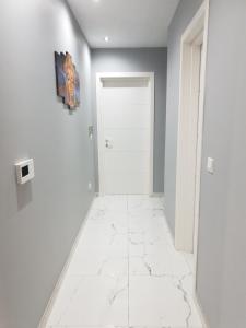 a hallway with a white tile floor and a white door at A Ground Floor Maisonette - Mellieha Bay in Is-Sellum