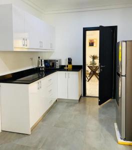Una cocina con gabinetes blancos y un refrigerador negro. en MILTON AVENUE SUITES, 2Bed, en Accra