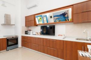 eine Küche mit Holzschränken und einem TV an der Wand in der Unterkunft Ibiscus and Lily Apartments in Rhodos (Stadt)