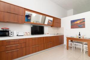 eine Küche mit Holzschränken und einem Tisch mit Mikrowelle in der Unterkunft Ibiscus and Lily Apartments in Rhodos (Stadt) + 33 Fotos