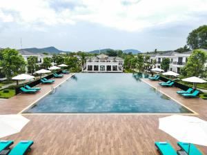 an overhead view of a large swimming pool with chairs and umbrellas at DAD Resort Phú Quốc in Phú Quốc