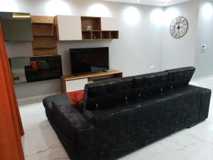 a black leather couch in a living room with a clock at A Ground Floor Maisonette - Mellieha Bay in Is-Sellum