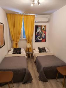 two beds in a small room with yellow curtains at Batala1-City marina apartment with secured private parking in Dubrovnik