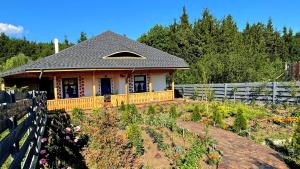 a house with a garden in front of a fence at Pensiunea „Căsuța cu maci” in Iaşi