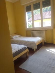 Duas camas num quarto com uma janela em Casa Patrone appartamento Luigi em Nebbiuno