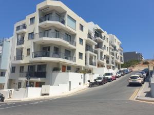 a white apartment building with cars parked in front of it at A Ground Floor Maisonette - Mellieha Bay in Is-Sellum