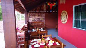 eine Terrasse mit einem Tisch, Stühlen und einer roten Wand in der Unterkunft Pousada Solar Maia Costa in Atins