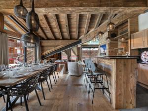 Un comedor con techos de madera y mesas y sillas. en Chalet luxueux avec 5 chambres, hammam, cheminée et grande terrasse au cœur de Val d'Isère - FR-1-567-34, en Val dʼIsère