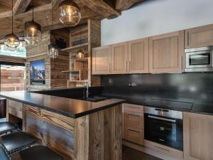 Una cocina con gabinetes de madera y una encimera negra. en Chalet luxueux avec 5 chambres, hammam, cheminée et grande terrasse au cœur de Val d'Isère - FR-1-567-34, en Val dʼIsère 9 fotos más