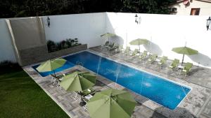 uma piscina com guarda-sóis e cadeiras verdes ao lado de uma piscina em Hotel Las Puertas de Tepoztlan em Tepoztlán