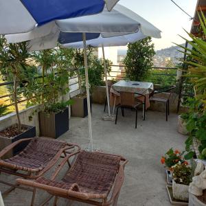 eine Terrasse mit einem Tisch, Stühlen und einem Sonnenschirm in der Unterkunft Bugenvilija in Budva