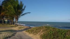 a dirt road next to the ocean with palm trees at Pousada Ana Raio in Alcobaça