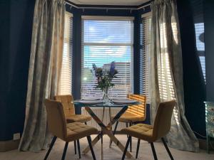 a table with chairs and a vase of flowers in a window at Elberry at Dart Valley Coastal Apartments in Paignton