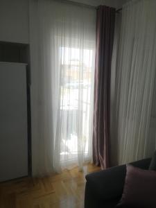 a living room with a window with curtains and a couch at Jednosoban stan Zoja in Podgorica