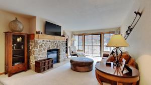 a living room with a stone fireplace and a table at Spacious One Bedroom Condo in Mammoth! Free Assigned Parking - Snowbird 107 in Mammoth Lakes