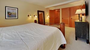 a bedroom with a large white bed and a staircase at Spacious One Bedroom Condo in Mammoth! Free Assigned Parking - Snowbird 107 in Mammoth Lakes