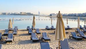迪拜Luxury Apartment Palm Jumeirah的海滩上的一组椅子和遮阳伞