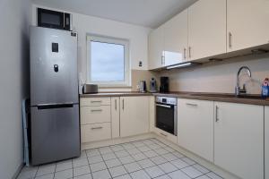 cocina con armarios blancos y nevera de acero inoxidable en Apartment Sun Balcony Dresden Friedrichstadt, en Dresden