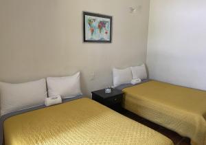 a room with two beds and a picture on the wall at Hotel Allende Morelia in Morelia