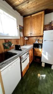 eine Küche mit Holzschränken und einem weißen Kühlschrank in der Unterkunft Cosy Lodge in Madonna di Campiglio