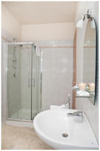 baño blanco con ducha y lavamanos en Appartamenti Sant' Andrea, en Trapani