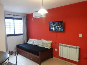 a bedroom with a red wall with a bed and a fan at Abuela Chela in Villa Carlos Paz