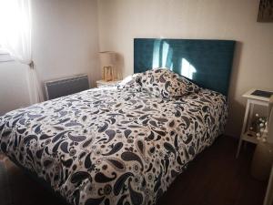 a bed with a black and white comforter in a bedroom at Maison 3 étoiles avec jardin pour familles, sportifs, curistes... in Digne-les-Bains