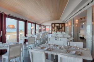 a restaurant with white tables and chairs and windows at GH Palazzo Suite & SPA in Livorno