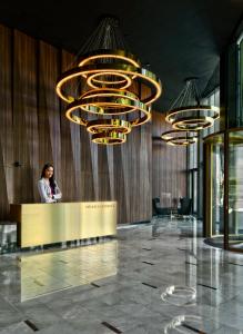 a woman standing at a counter in a lobby with chandeliers at Mennica Residence Luxury Location in Warsaw