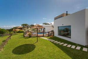 einen Garten mit einem Sonnenschirm und einem Pool in der Unterkunft BeGuest SunRoca Suites in Colares
